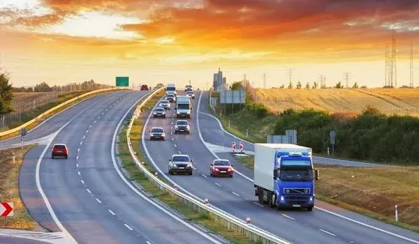 Wide multi-lane highway carrying cars and trucks under an open sky